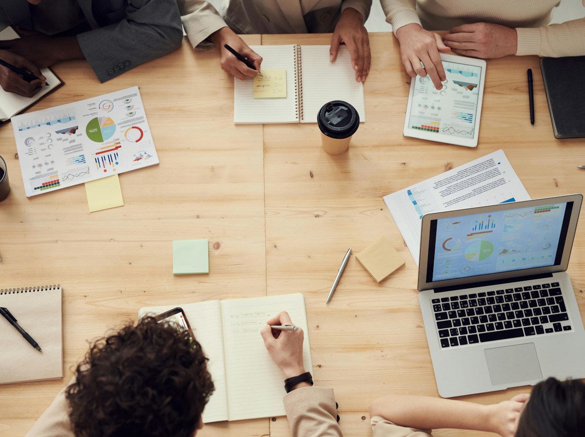 Looking down at a desk where people are working together. An example of the team building facilitation that The Learning Lounge can offer. Photo by fauxels: https://www.pexels.com/photo/photo-of-people-having-meeting-3183186/